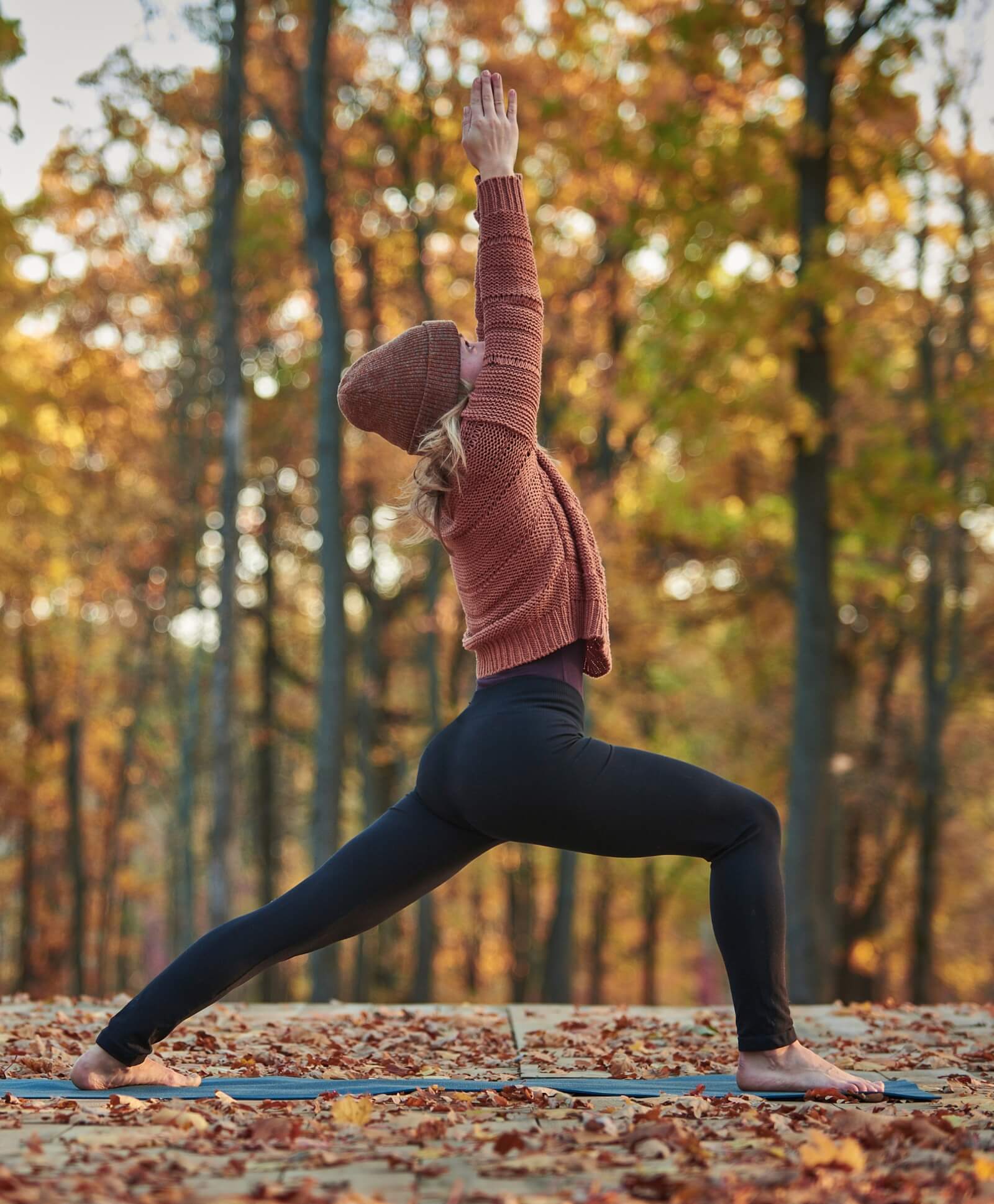 Young woman practicing yoga outside surround by autumn leaves